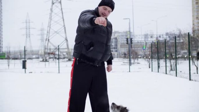 冬季天气下，男子主人在街上训练狗。可爱的狗一起跳训练主人在冬季散步。