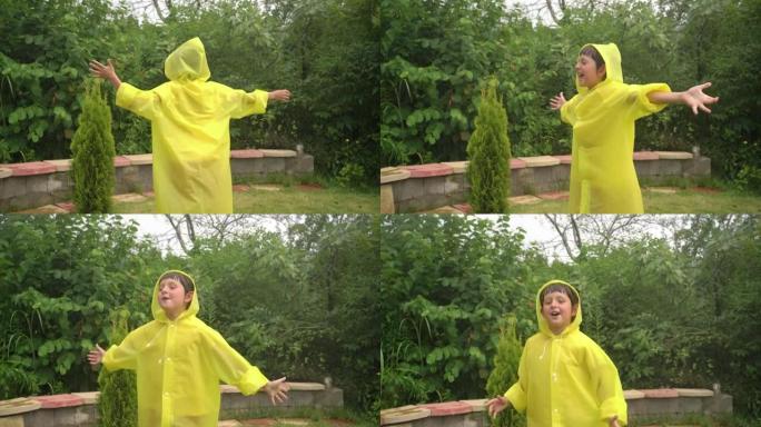 有趣的快乐男孩举起手穿着黄色雨衣跳舞在降雨时玩得开心
