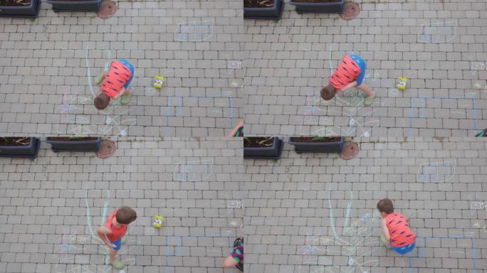 短片显示年轻的男孩和女人在前院用彩色粉笔铺路板上画画。瑞典。