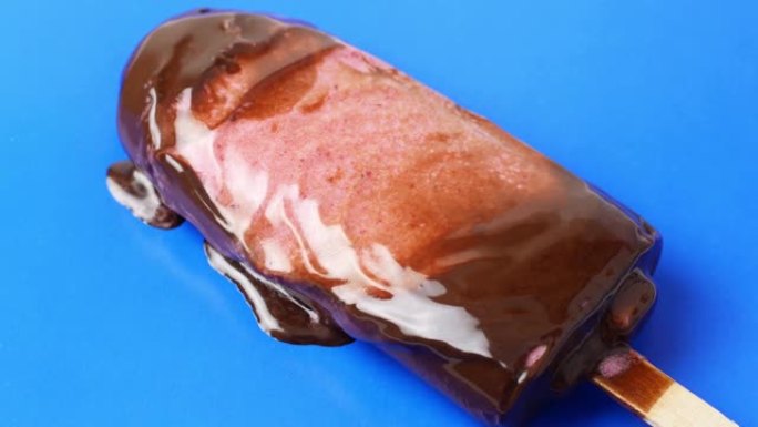 巧克力冰淇淋圣代躺在蓝色背景上，融化缓慢。4k视频美食特写。