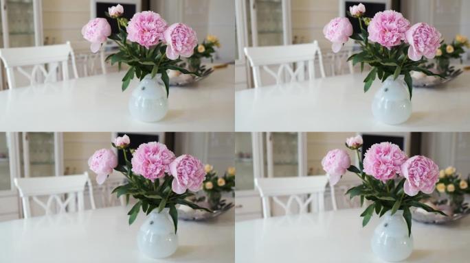 粉红色牡丹和黄色玫瑰在大桌子上的白色花瓶在现代灯光室内