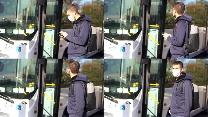 在大流行新型冠状病毒肺炎期间，年轻的白人男子戴着口罩，在乘公共汽车时看着莫比尔
