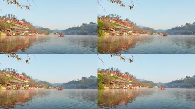 在泰国湄宏顺班拉泰国村的背景下，一艘中国风船在湖雾迷雾和乡村山上航行