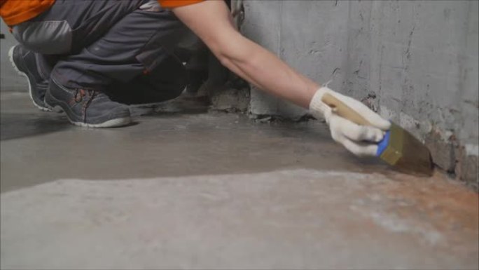 工人用水涂抹混凝土地板进行加工。防水混凝土地板。工人在给地板防水之前做了一个初步步骤