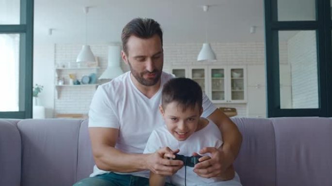 父亲拥抱儿子，同时积极玩摇杆上的电脑游戏，看着屏幕，并在获胜时表达快乐和兴奋。4k视频片段