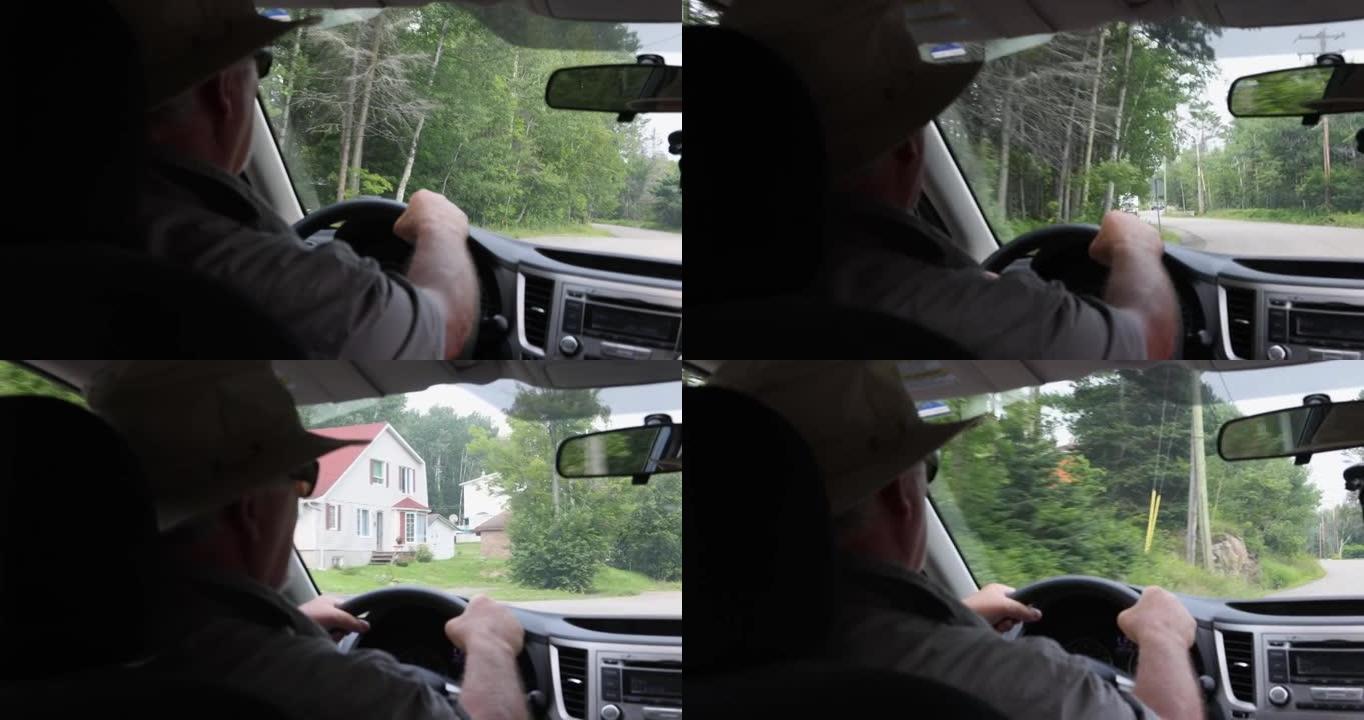 在加拿大乡村道路上行驶的高级男子的后视图