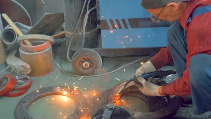 侧视图一名老年男性铁匠在没有眼镜防护面罩的情况下工作，用焊接机焊接金属零件