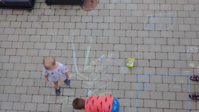 短片显示了两个男孩在用彩色粉笔铺路板上绘画的俯视图。瑞典。