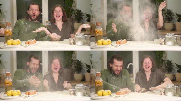 一对夫妇正在厨房里准备面粉面团。快乐的男人和女人玩得开心，微笑。为了搬家的快乐，在新家中鼓掌面粉。一