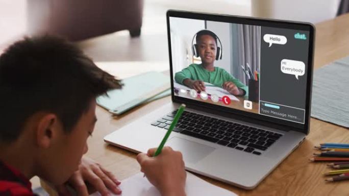亚洲男孩在家里做作业并与笔记本电脑上的同学进行视频通话
