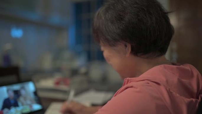 亚洲华裔高级妇女晚上在厨房视频通话中使用数字平板电脑与儿子和儿媳交谈