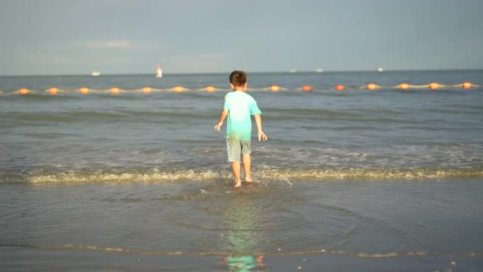 亚洲孩子在海滩上慢动作散步和跑步。自由和假期的概念