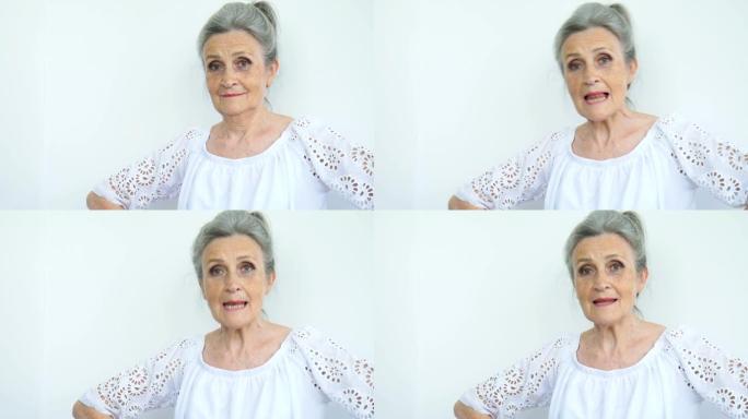 美丽的老奶奶白发，满脸皱纹，看着白色背景上的相机，母亲节，退休快乐