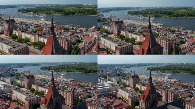 河岸上城市的鸟瞰图。有大型建筑的主要宽阔街道。在圣玛丽教堂红色瓷砖屋顶和塔楼上方飞行