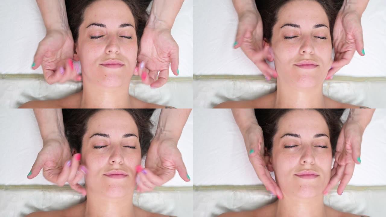 美容师用润肤霜在女人脸上做面部按摩。高质量4k镜头
