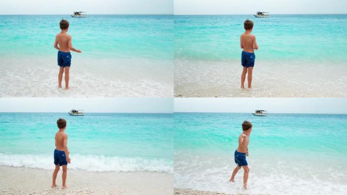 小男孩在海边扔石头。