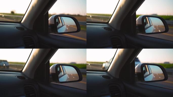 在日落灯光下在高速公路上快速行驶的侧镜车中观看。