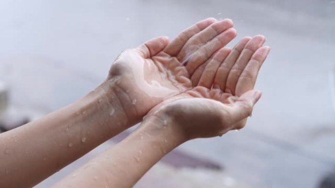 两只手握着落雨，雨天，暴风雨季节，手掌上接雨，雨季慢动作，在街道一侧，空气潮湿冷凝，酸雨测量，隔离特