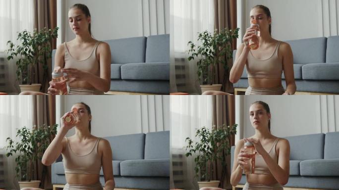 穿着运动服的欧洲女孩从瓶子里喝水，坐在莲花的位置