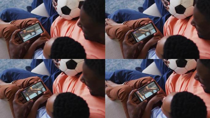 父亲和儿子在家里观看智能手机上的田径比赛的合成