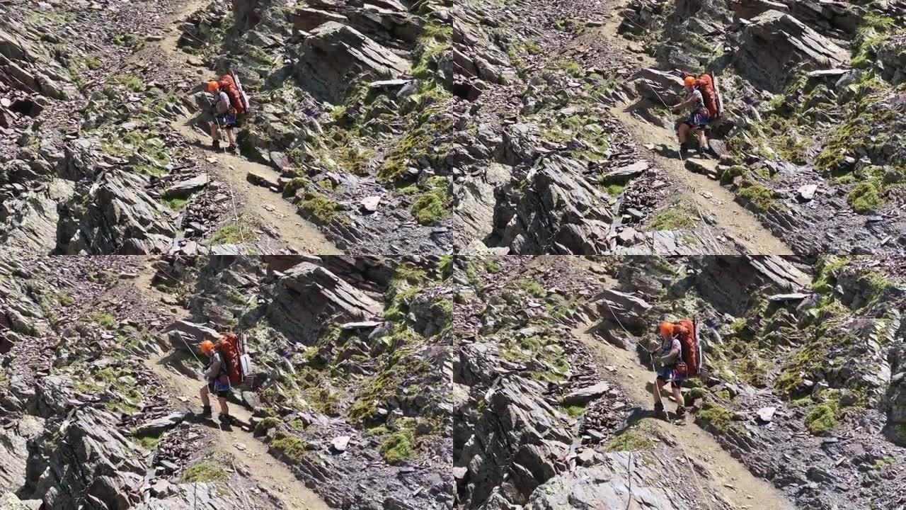 一名游客沿着山间小路从悬崖上下来，抓住垂直栏杆的绳子