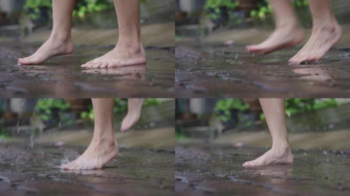 下雨天，女性赤脚在水坑上跳跃和玩耍的低角度，在街道边的人行道上倾盆大雨，有趣的时间泼水，四处跳跃，无