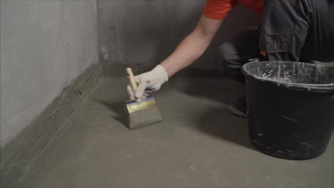 用刷子和砂浆给地板防水。地板防水。主人用刷子处理地板