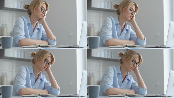 戴眼镜的女孩看着笔记本电脑睡着了，正在攻读文凭的学生