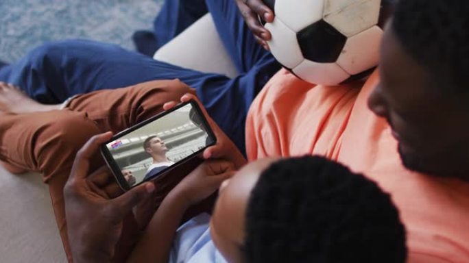父亲和儿子的合成在智能手机上观看橄榄球比赛