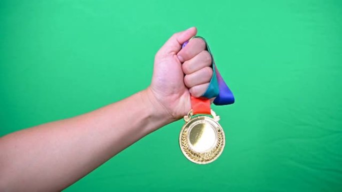 男子在绿色背景上举起金牌