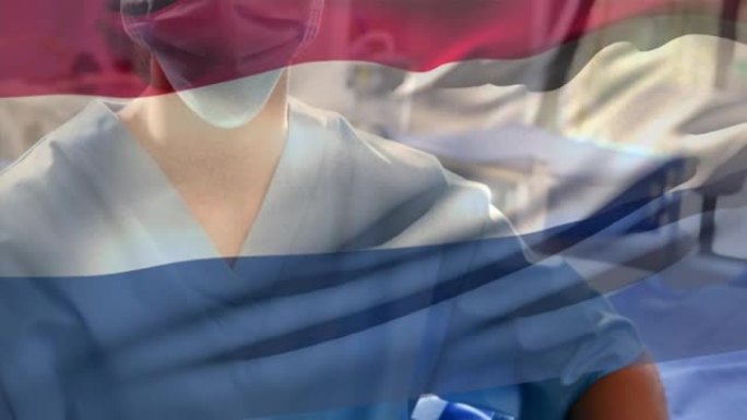荷兰国旗在医院挥舞着戴着口罩的白人女性卫生工作者
