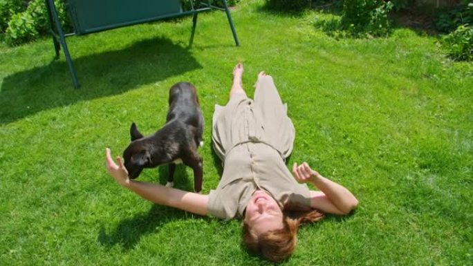 夏天，一个年轻女孩和一只狗在草坪上玩耍，她一边舔一边享受，一边抓着它。Prores422。