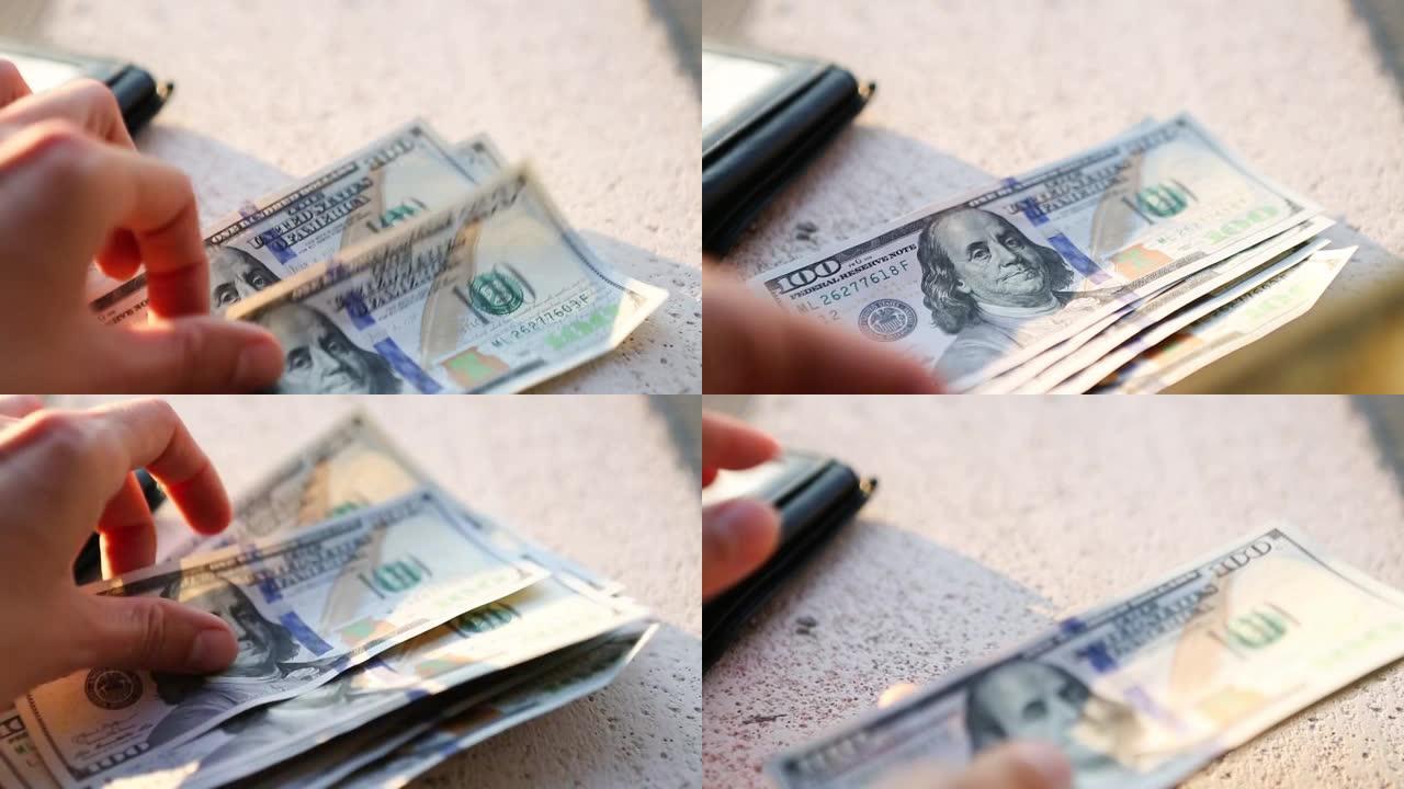 手将一百美元的钞票堆成一堆，然后拿一张钞票。现金，一叠100美元的钞票特写。金融，经济，金融规划，经