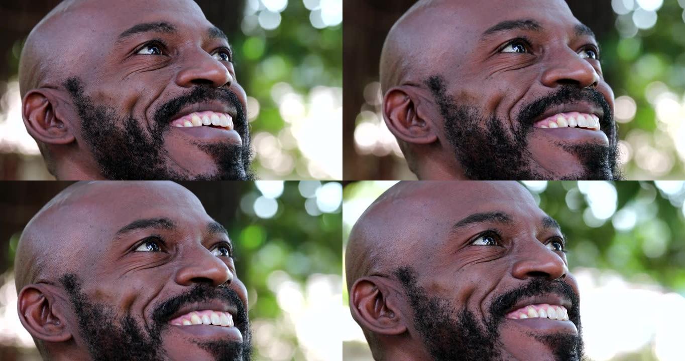 快乐的非洲男人抬头看着天空微笑，黑人充满希望和信念