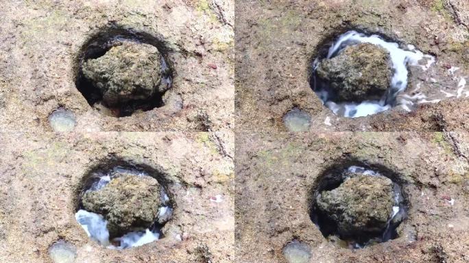 潮汐上升时，岩石上的天然洞被水覆盖-海洋的海水进入石头的圆形孔口