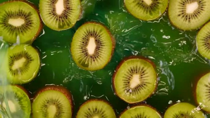 猕猴桃切片以慢动作溅入水或猕猴桃汁中。美味的绿色夏季水果。