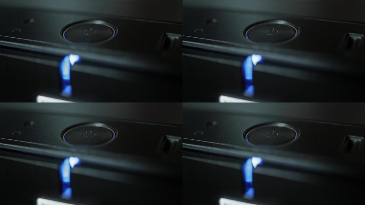 带蓝色指示灯的电脑关机电源按钮。现代技术，宏观