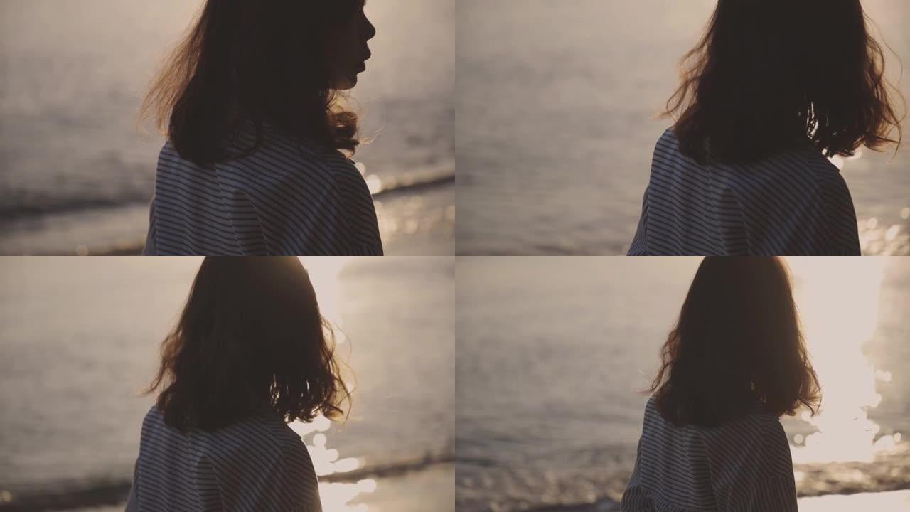 快乐的年轻女子走到海边美丽的落日剪影