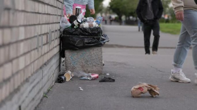 垃圾，人们扔掉垃圾，满满的垃圾箱，垃圾躺在城市的街道上。人们走过垃圾