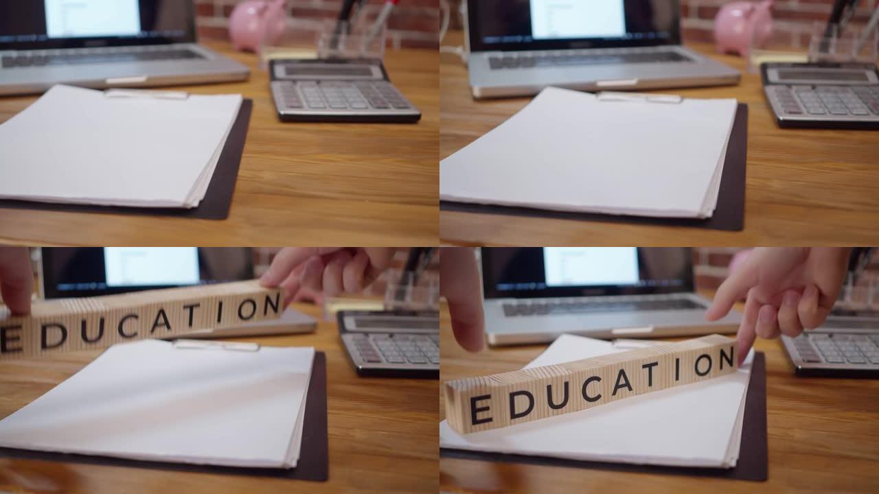 由木制立方体制成的铭文教育放置在带有文具和笔记本电脑的办公桌上。带有铭文的立方体放在办公室的桌子上。