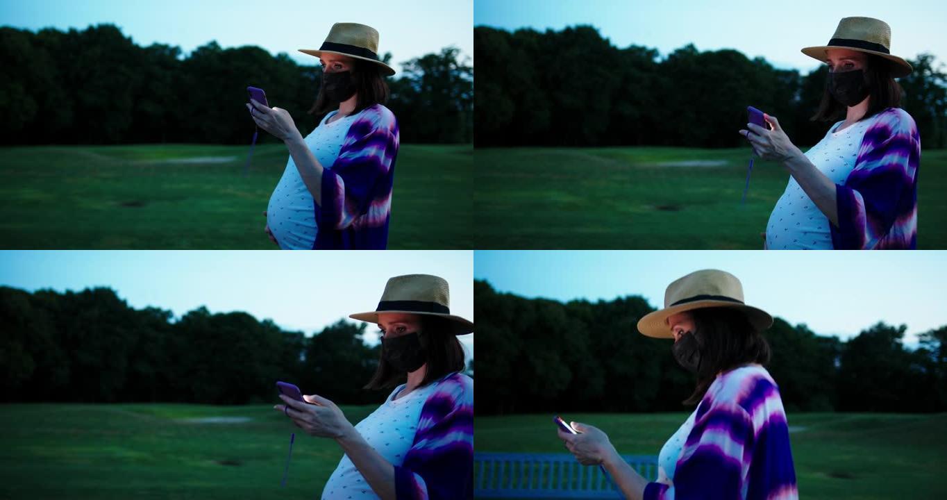 怀孕的白人妇女戴着医用口罩并使用智能手机在公共场所行走