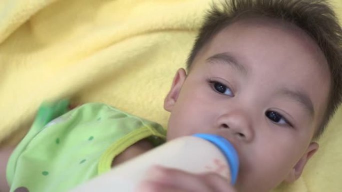 亚洲婴儿在床上喝奶瓶中的牛奶