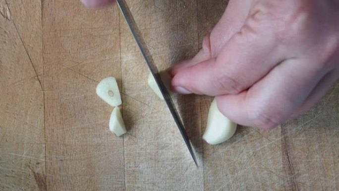 一瓣大蒜是由厨师在木砧板上切的。