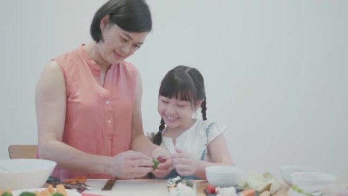孩子在母亲的帮助下在家做寿司来学习烹饪