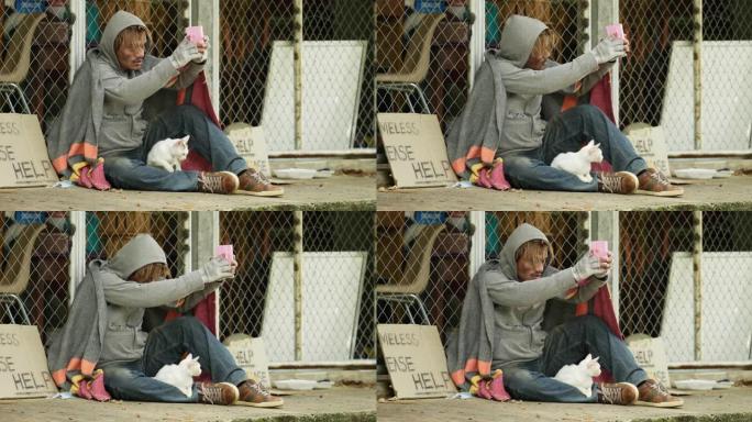 无家可归，穿着脏衣服，拿着旧毯子和猫