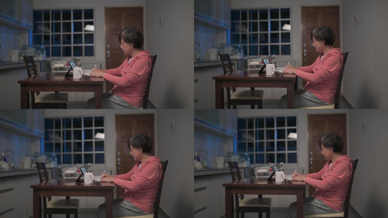 亚洲华裔高级妇女晚上在厨房视频通话中使用数字平板电脑与儿子和儿媳交谈