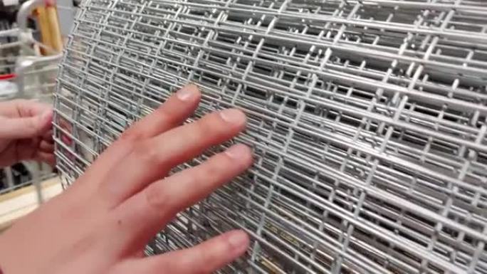 一名男子在建材商店中选择金属补强网，特写