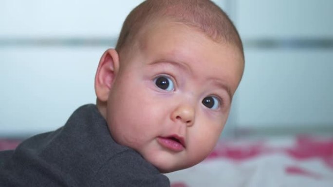 相机特写镜头中婴儿的样子。一个可爱的小宝宝正对着镜头看。照顾孩子的理念，父母的爱。