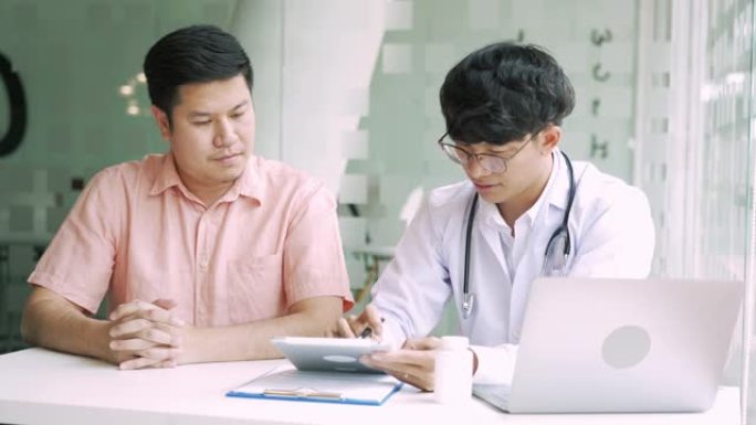 亚洲医生在诊所谈论病人，同时使用药片解释病人的情况和治疗结果。