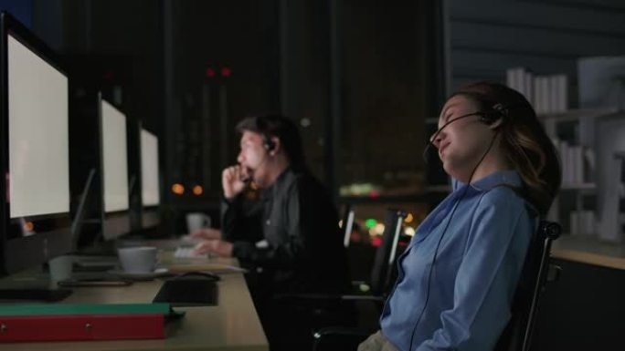 热线接线员。呼叫中心员工晚上在现代办公室使用电脑和耳机